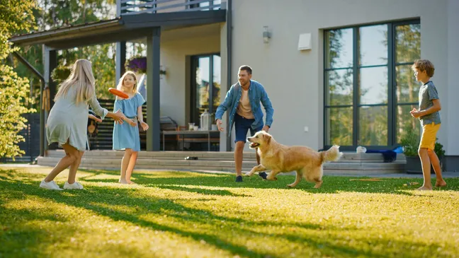 Family playing with a golden retriever outside in a garden